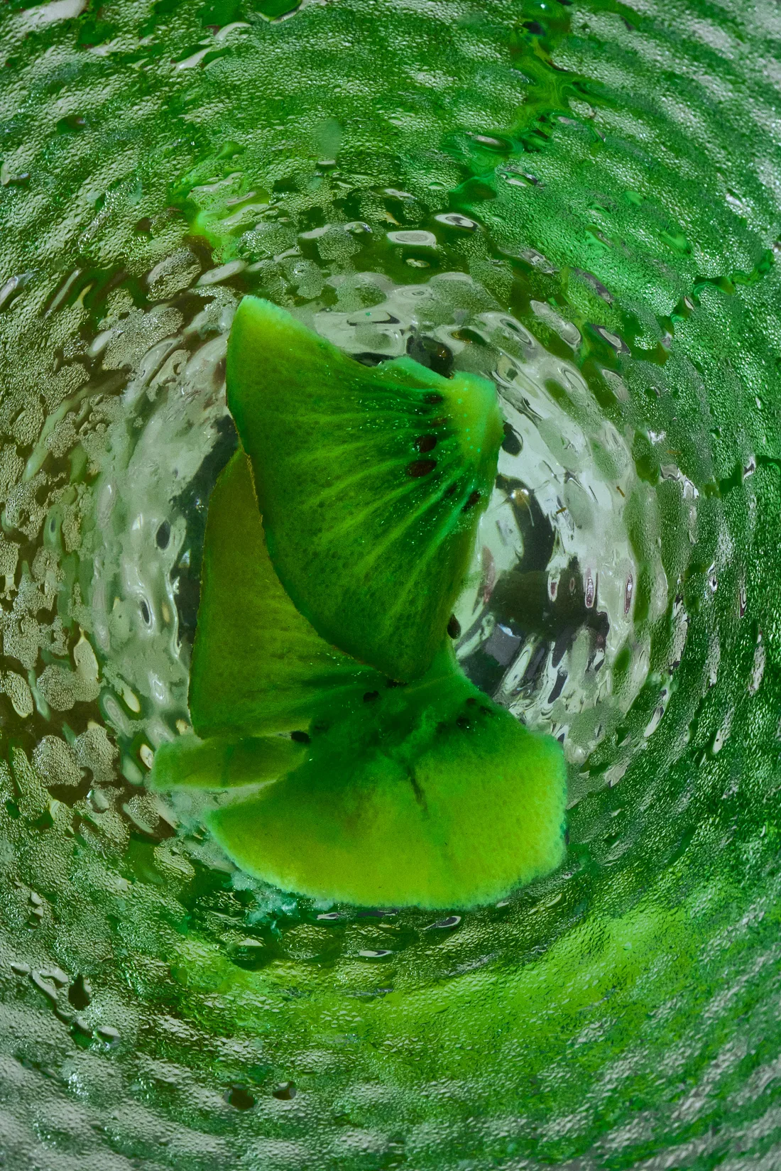 Fresh kiwi in sparkling green water, vitamins up close